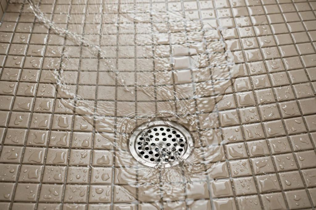 Water flowing toward a shower floor drain in a bathroom